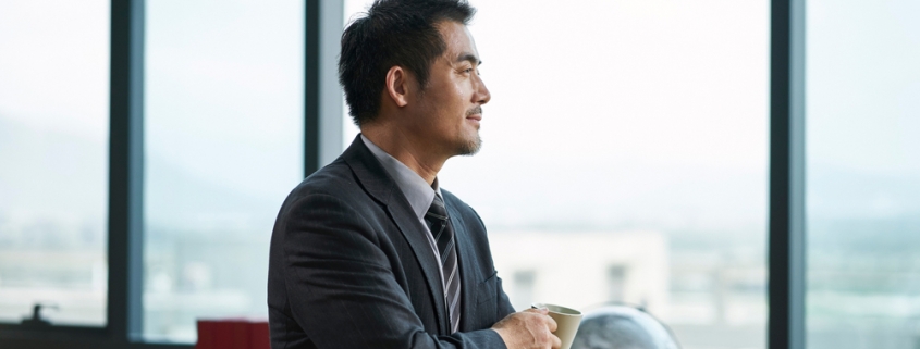 Asian businessman, thinking while gazing out office window